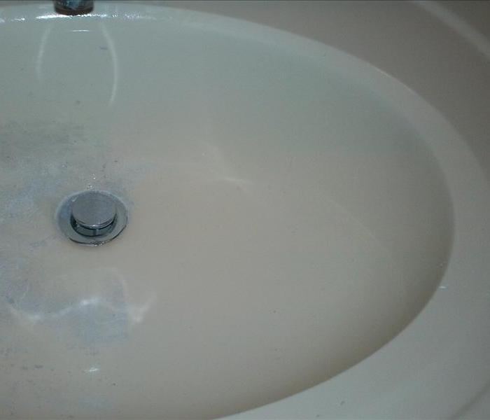 Bathroom sink showing the cleaning in the process.  Half clean and the other half still covered in construction debri. 