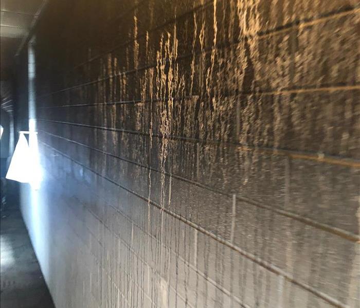 Apartment complex hallway after a fire that has completely covered the surfaces in smoke and soot