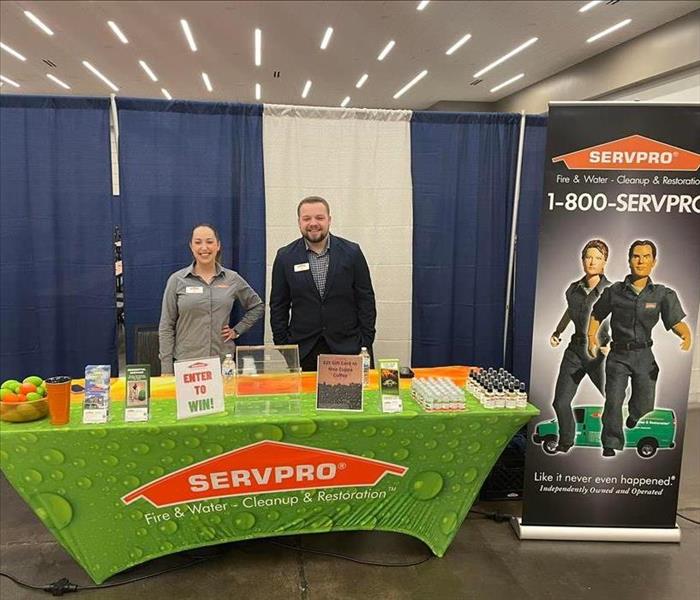 A man and woman standing at a SERVPRO table