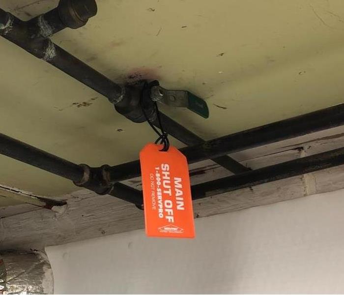A water shut off valve with an orange SERVPRO tag on it