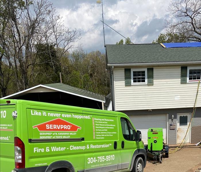 A green SERVPRO van in front of a water damaged home.